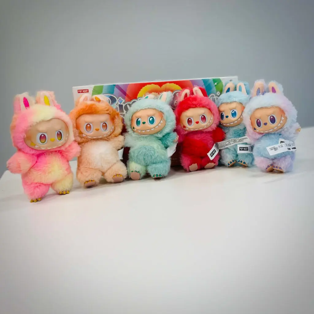 6 Labubu Big Into Energy dolls standing on office table with the box of complete set behind them