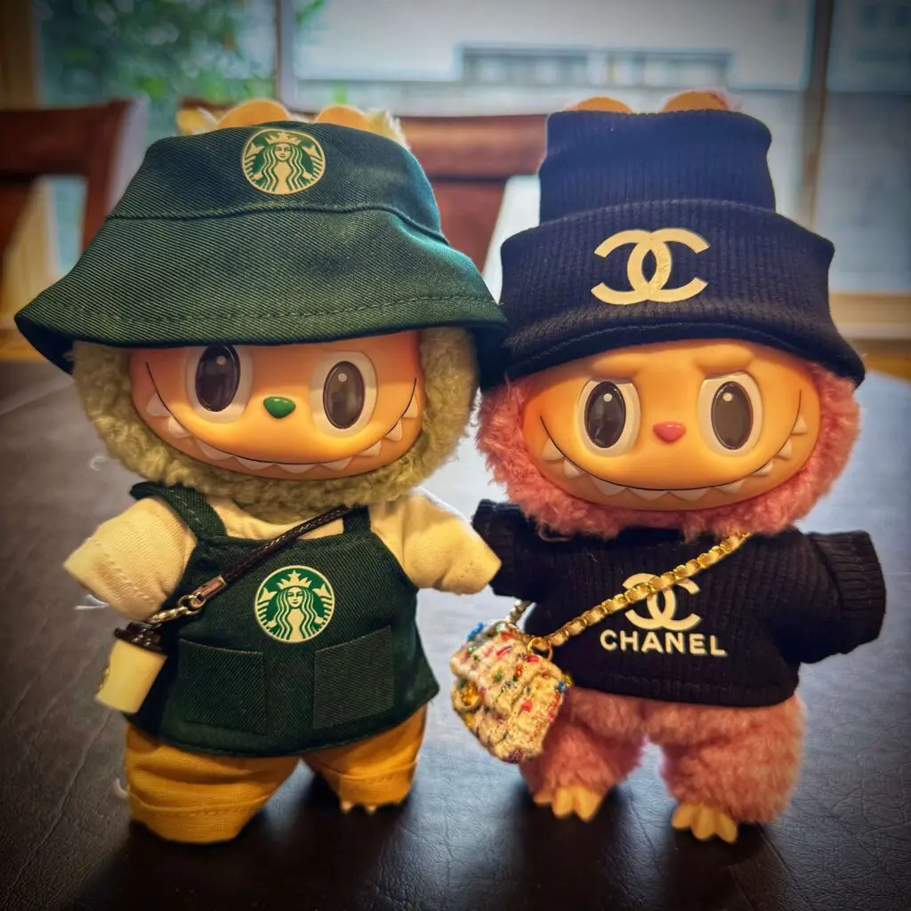 Green Grape and Lychee Berry from Labubu Exciting Macaron series dressed in Starbucks and Chanel outfit on black table