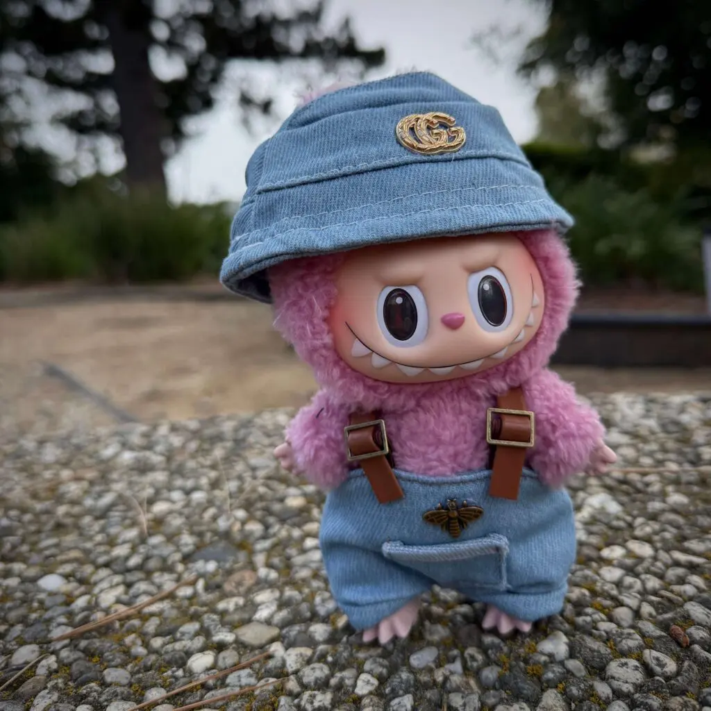 Labubu Lychee Berry all dressed up in blue denin outfit and overalls standing in a park on concrete bench
