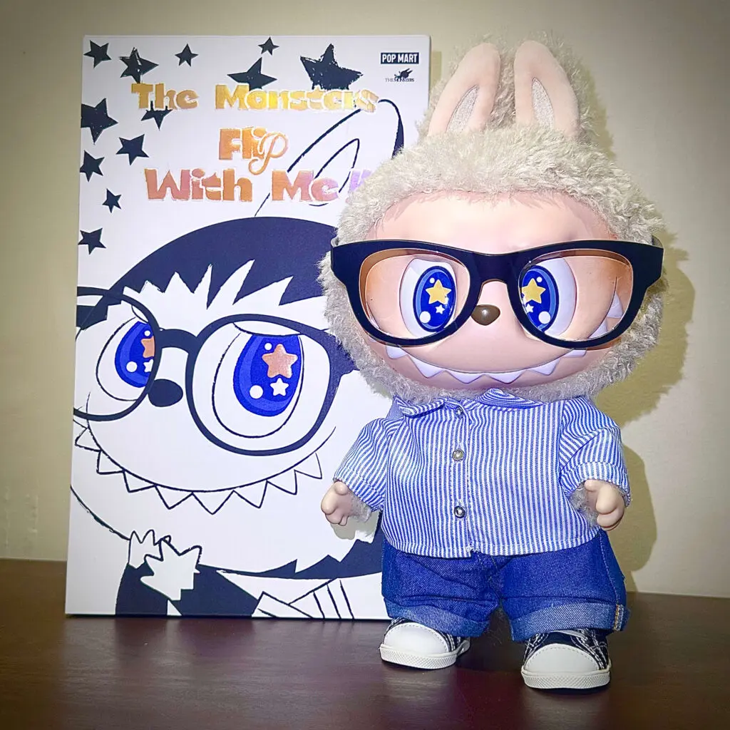 Labubu Flip with Me with glasses standing on a table next to the box from Pop Mart