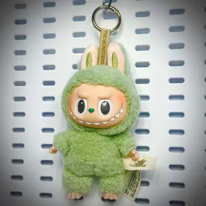 Labubu Green Grape doll from Exciting Macaron series hanging on a white pegboard