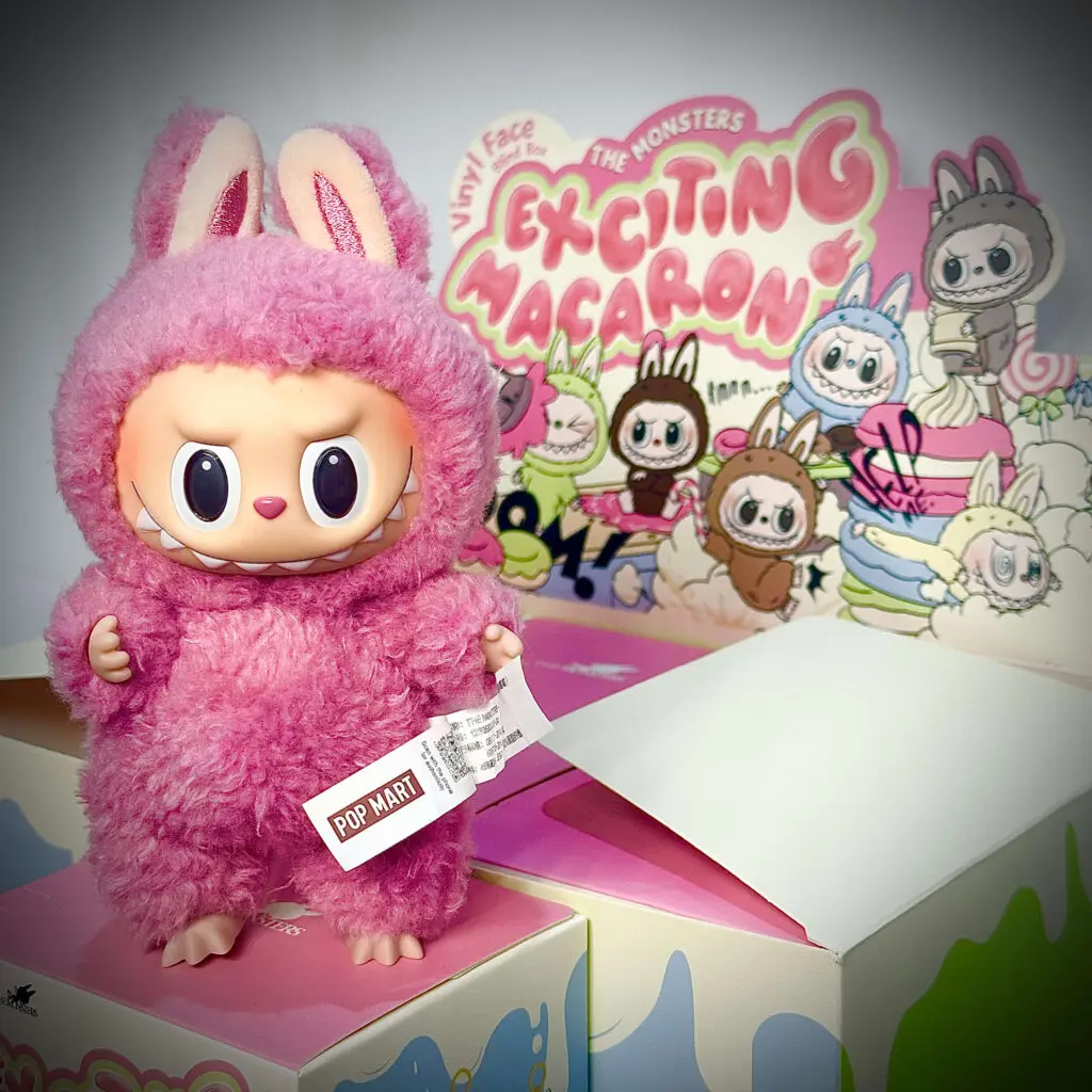 Labubu Lychee Berry standing on an opened blind box with boxed set behind