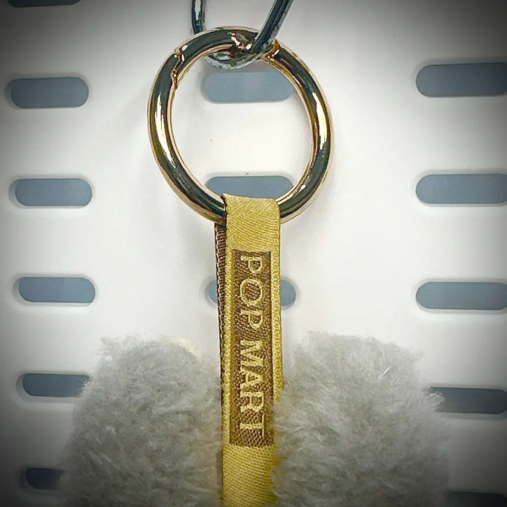 Back view of Labubu Sesame Bean pendant with embroidered branding