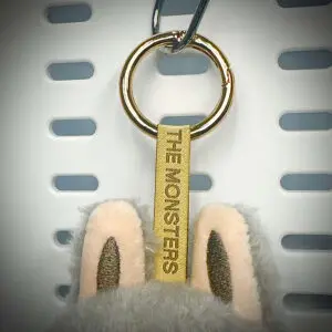 Close-up of Labubu Sesame Bean pendant with embroidered lanyard and gold hardware