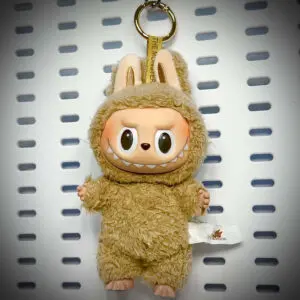 Labubu Toffee doll from Exciting Macaron series hanging on a white pegboard