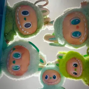 5 Labubu green dolls of different shades of green looking down