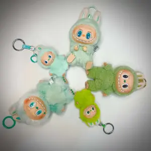 5 green Labubu keychain dolls laid down next to each other to form a circle