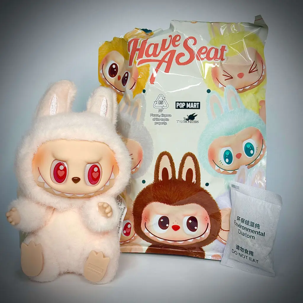 Labubu doll Dada from Have a Seat series sitting next to pouch and dehumidification packet