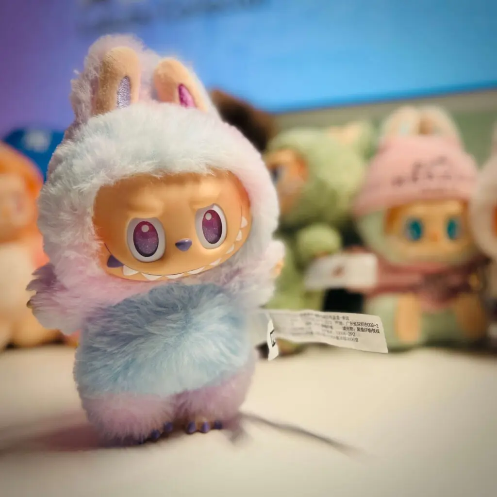 Labubu doll called Luck from the Labubu Big Into Energy series standing on work desk with other dolls behind her