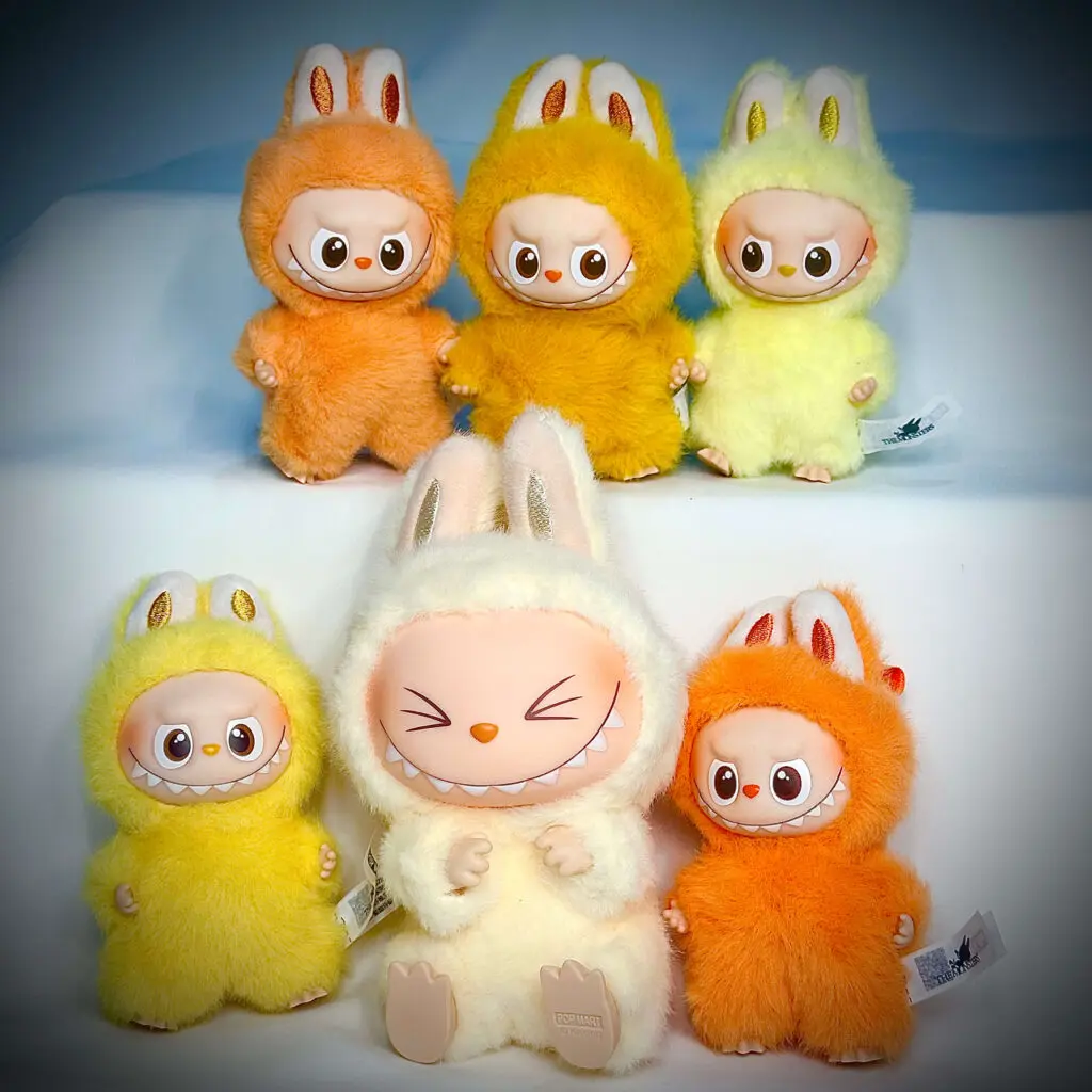 Orange and yellow Labubu dolls next to each other with spotlight and white background