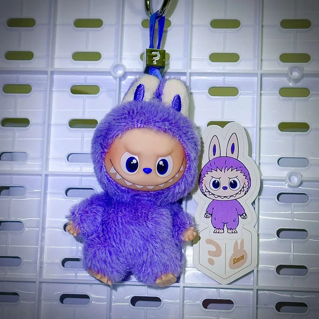 Mini Labubu Pin For Love Emm ? hanging on a white pegboard with sticker name