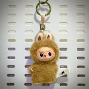 Labubu Pin for Love "B" Belief hanging on a board