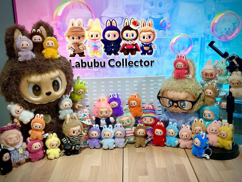 Group picture of our collection of different Labubu dolls in front of my other iMac work computer