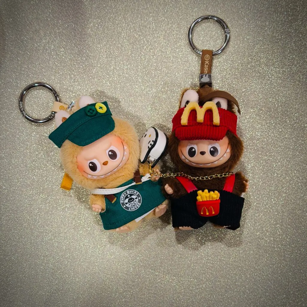 Labubu Pin for Love S in Starbucks outfit next to Labubu L in McDonalds outfit on breakfast table