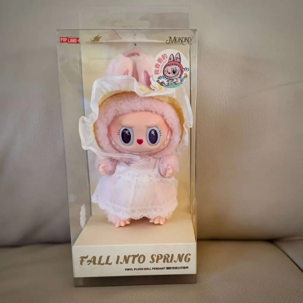 Labubu doll named Mokoko from Fall into Spring release (smaller keychain version) inside box and on white sofa