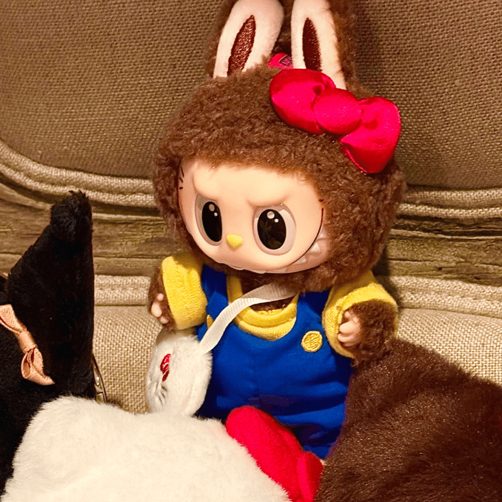 square crop of Labubu x Hello Kitty and Friends secret keychain doll Classic Hello Kitty on a pile of other plush toys