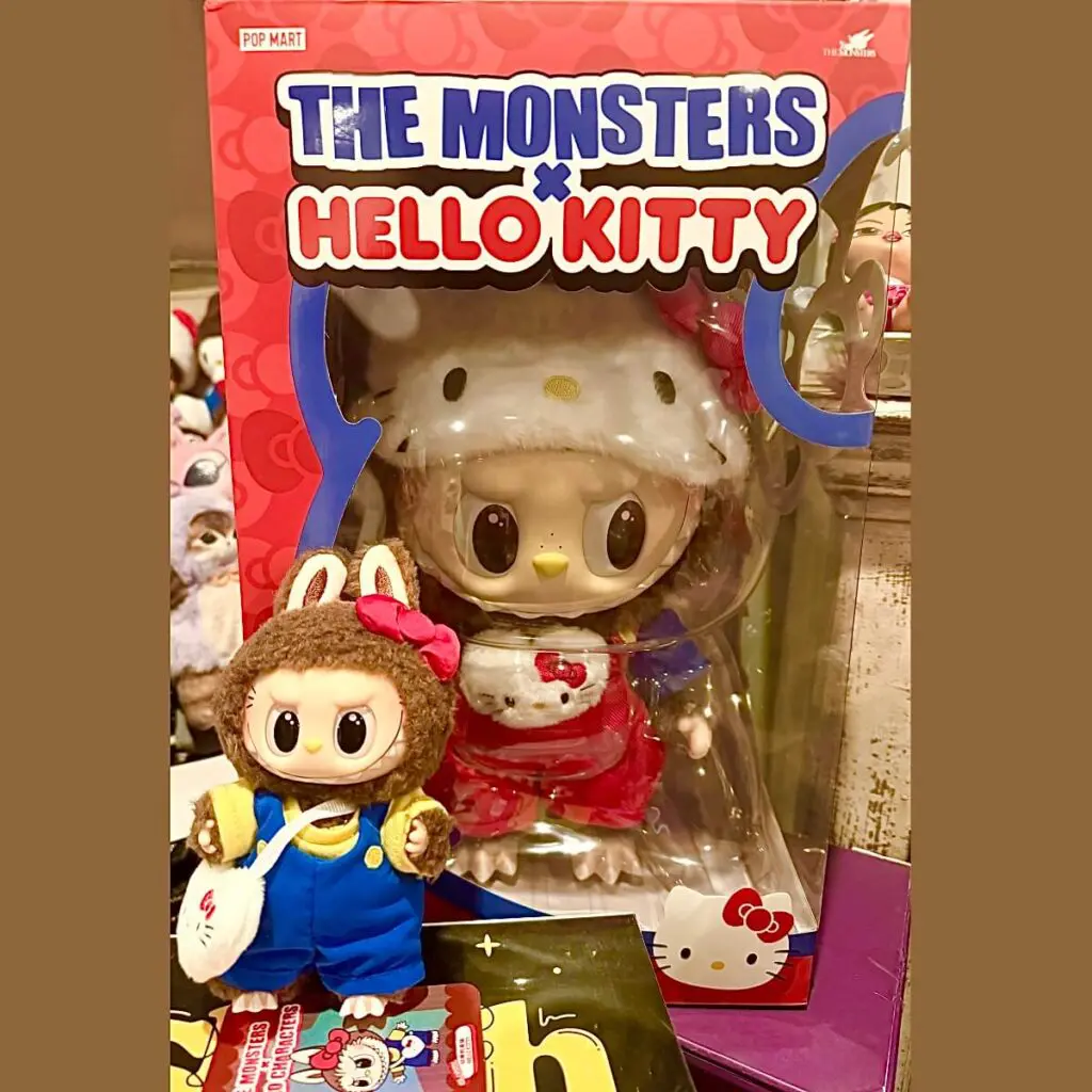 Labubu x Hello Kitty plush doll inside original box packaging beside secret Classic Hello Kitty keychain doll.