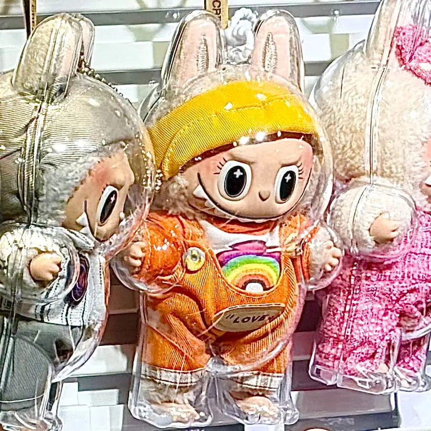 lafufu soymilik keychain doll wearing a matching orange outfit hanging on a store display