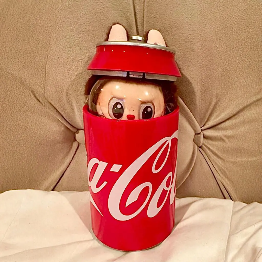 Coca-Cola Labubu doll secret Mysterious guest on a brown sofa